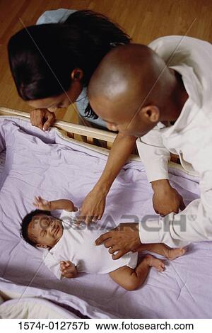 High angle view of parents looking at their son in a crib View Large Photo Image Stock Image - High angle view of parents looking at their son in a crib. Fotosearch