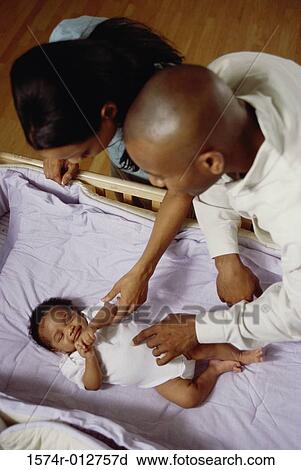 Stock Image - High angle view of parents looking at their son in a crib. Fotosearch