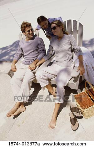 Stock Image - High angle view of parents sitting in chairs with their daughter standing behind them. Fotosearch