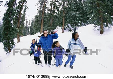 Stock Image - High angle view of parents walking with their two children in snow. Fotosearch