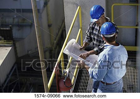 Stock Photograph - High angle view of two foremen holding blueprints. Fotosearch