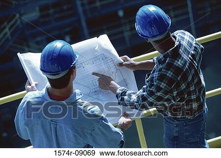 Stock Photo - High angle view of two foremen working on blueprints. Fotosearch