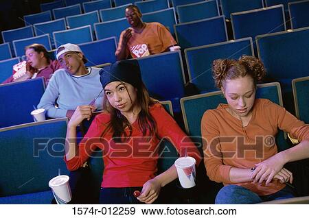 Stock Photo - High angle view of two teenage girls sitting in a movie theater. Fotosearch