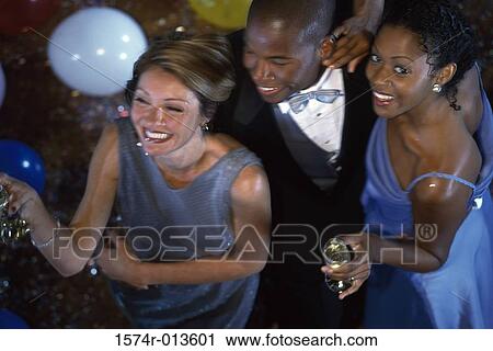 Stock Image - High angle view of two young women and a young man smiling at a party. Fotosearch