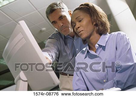 Stock Photograph - Low angle view of a businessman and a businesswoman in an office. Fotosearch