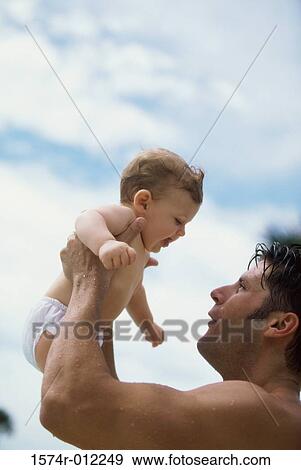 Low angle view of a father picking up his son View Large Photo Image Stock Photo - Low angle view of a father picking up his son. Fotosearch