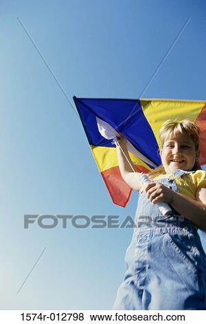 Low angle view of a girl flying a kite View Large Photo Image Stock Photo - Low angle view of a girl flying a kite. Fotosearch
