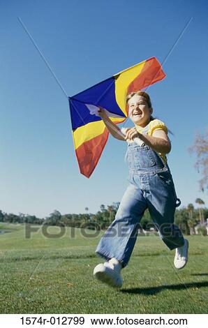 Low angle view of a girl flying a kite View Large Photo Image Stock Photo - Low angle view of a girl flying a kite. Fotosearch