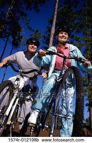 Low angle view of a mature couple riding their bicycles View Large Photo Image Stock Image - Low angle view of a mature couple riding their bicycles. Fotosearch