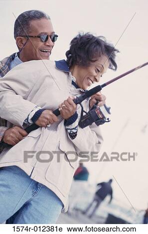 Stock Image - Low angle view of a mature couple fishing together. Fotosearch