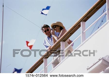 Low angle view of a mature woman taking a photograph with a mature man standing beside her on a cruise ship View Large Photo Image Picture - Low angle view of a mature woman taking a photograph with a mature man standing beside her on a cruise ship. Fotosearch