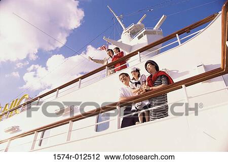 Stock Image - Low angle view of a mid adult couple with their daughter standing on the deck of a cruise ship. Fotosearch