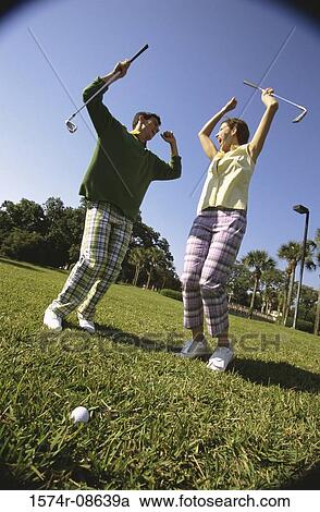 Stock Image - Low angle view of a mid adult man and a mid adult woman at a golf course. Fotosearch