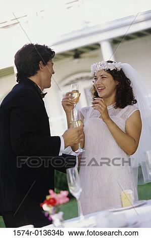 Stock Image - Low angle view of a newlywed couple toasting with champagne. Fotosearch