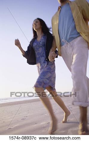 Low angle view of a young couple walking together at the beach View Large Photo Image Stock Image - Low angle view of a young couple walking together at the beach. Fotosearch