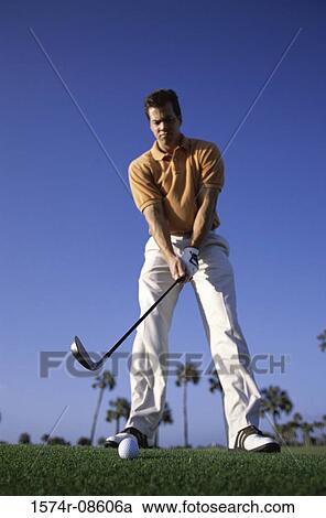 Stock Image - Low angle view of a young man playing golf. Fotosearch