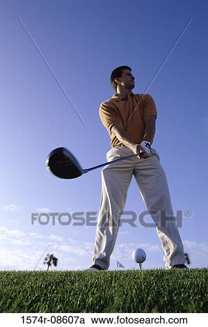 Stock Image - Low angle view of a young man playing golf. Fotosearch