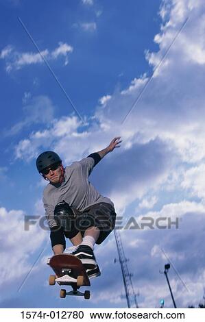 Low angle view of a young man skateboarding View Large Photo Image Stock Image - Low angle view of a young man skateboarding. Fotosearch