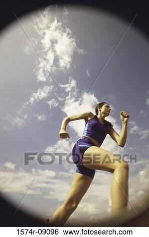 Low angle view of a young woman running View Large Photo Image Stock Photograph - Low angle view of a young woman running. Fotosearch