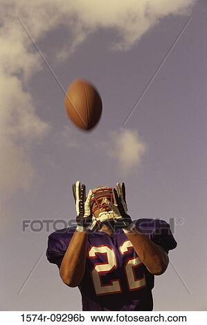 Stock Image - Low angle view of an American football player catching a ball. Fotosearch