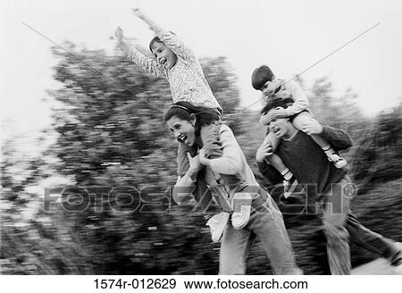 Low angle view of parents carrying their children on their shoulders View Large Photo Image Stock Photo - Low angle view of parents carrying their children on their shoulders. Fotosearch