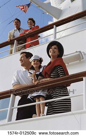 Stock Image - Low angle view of parents with their daughter standing on the deck of a cruise ship. Fotosearch