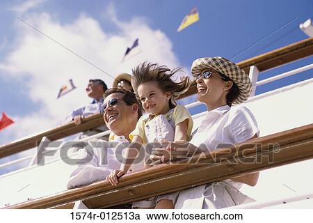 Stock Image - Low angle view of parents with their daughter standing on the deck of a cruise ship. Fotosearch