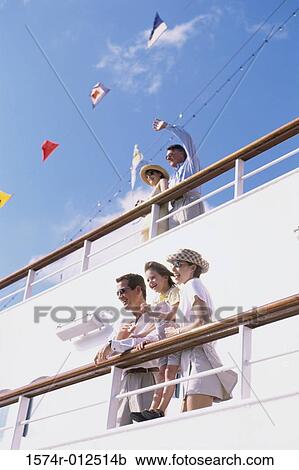 Stock Image - Low angle view of parents with their daughter standing on the deck of a cruise ship. Fotosearch