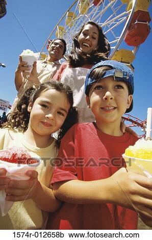 Stock Image - Low angle view of parents with their son and daughter in an amusement park. Fotosearch