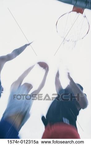 Low angle view of three men playing basketball View Large Photo Image Stock Image - Low angle view of three men playing basketball. Fotosearch