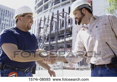 Low angle view of two foremen shaking hands standing at a construction site View Large Photo Image Stock Image - Low angle view of two foremen shaking hands standing at a construction site. Fotosearch