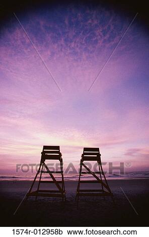 Stock Image - Low angle view of two lifeguard chairs on the beach at dusk. Fotosearch