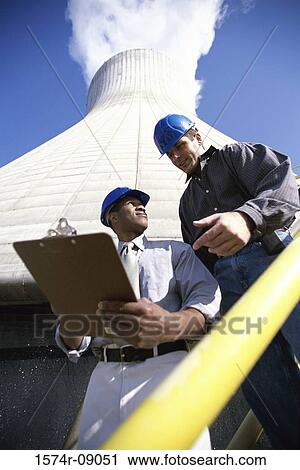 Low angle view of workers standing beside a smoke stack at a power plant View Large Photo Image Stock Image - Low angle view of workers standing beside a smoke stack at a power plant. Fotosearch