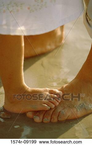 Stock Photo - Low section view of a child's feet on an adult's feet. Fotosearch