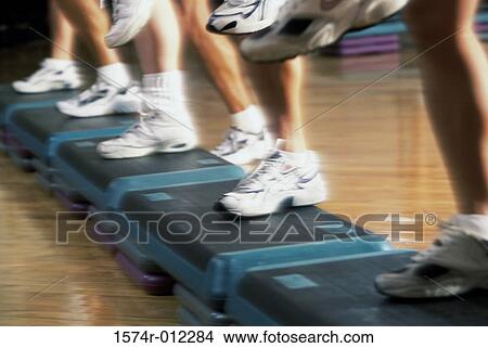 Picture - Low section view of a group of people doing step aerobics in a gym. Fotosearch
