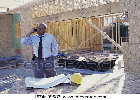 Male architect kneeling on the floor talking on a mobile phone View Large Photo Image Stock Photo - Male architect kneeling on the floor talking on a mobile phone. Fotosearch