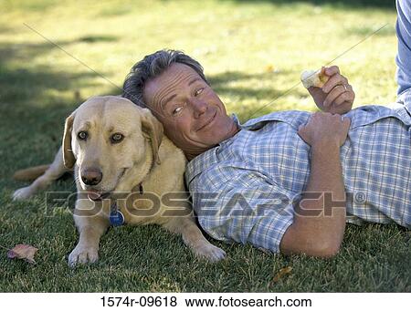 Man lying on a lawn with his dog View Large Photo Image Stock Photo - Man lying on a lawn with his dog. Fotosearch