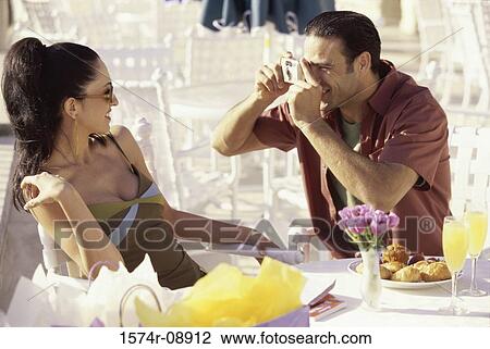 Stock Image - Man taking a photograph of a young woman. Fotosearch
