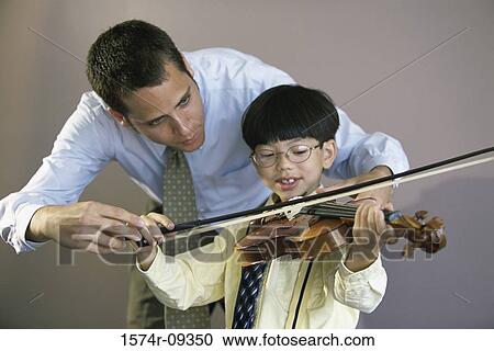 Stock Image - Man teaching a boy how to play the violin. Fotosearch