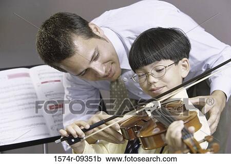 Stock Image - Man teaching a boy how to play the violin. Fotosearch
