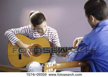 Man teaching a girl how to play the guitar View Large Photo Image Stock Photo - Man teaching a girl how to play the guitar. Fotosearch