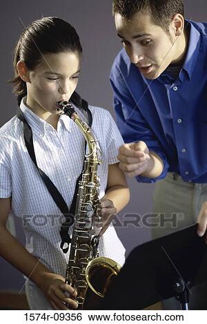 Stock Photograph - Man teaching a girl how to play the saxophone. Fotosearch