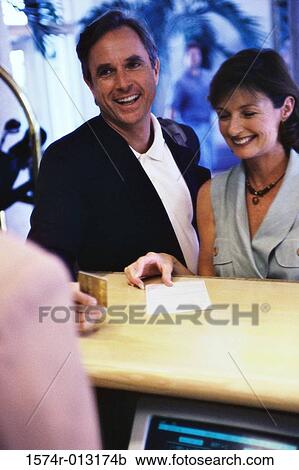 Mature couple making a payment with a credit card at a hotel reception desk View Large Photo Image Stock Image - Mature couple making a payment with a credit card at a hotel reception desk. Fotosearch