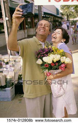 Mature couple taking a photograph of themselves in a market View Large Photo Image Stock Image - Mature couple taking a photograph of themselves in a market. Fotosearch