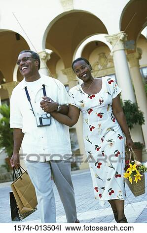 Stock Image - Mature couple walking with shopping bags. Fotosearch