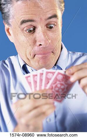 Stock Image - Mature man holding playing cards. Fotosearch