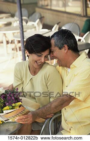 Stock Image - Mature man whispering to a mid adult woman. Fotosearch