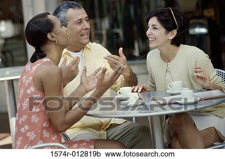 Mid adult couple and a young woman sitting together in a cafe View Large Photo Image Stock Image - Mid adult couple and a young woman sitting together in a cafe. Fotosearch