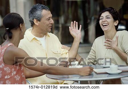 Mid adult couple and a young woman sitting together in a cafe View Large Photo Image Stock Image - Mid adult couple and a young woman sitting together in a cafe. Fotosearch