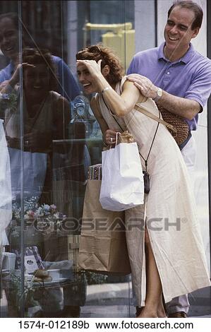 Mid adult couple standing in front of a window display of a store View Large Photo Image Stock Image - Mid adult couple standing in front of a window display of a store. Fotosearch